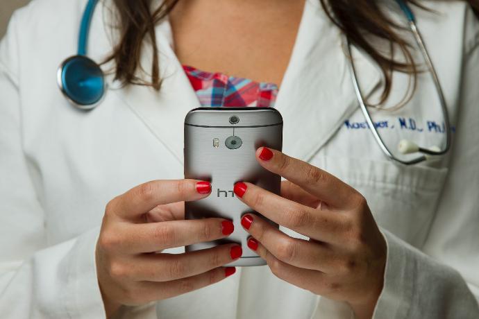 doctora revisando resultados de una prueba de ADN en su celular Una doctora revisando su celular para ver los resultados de las pruebas ADN para diagnóstico de enfermedades